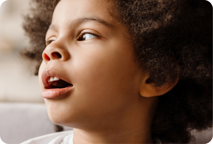 Close-up of a young child with curls looking upward with mouth open in surprise